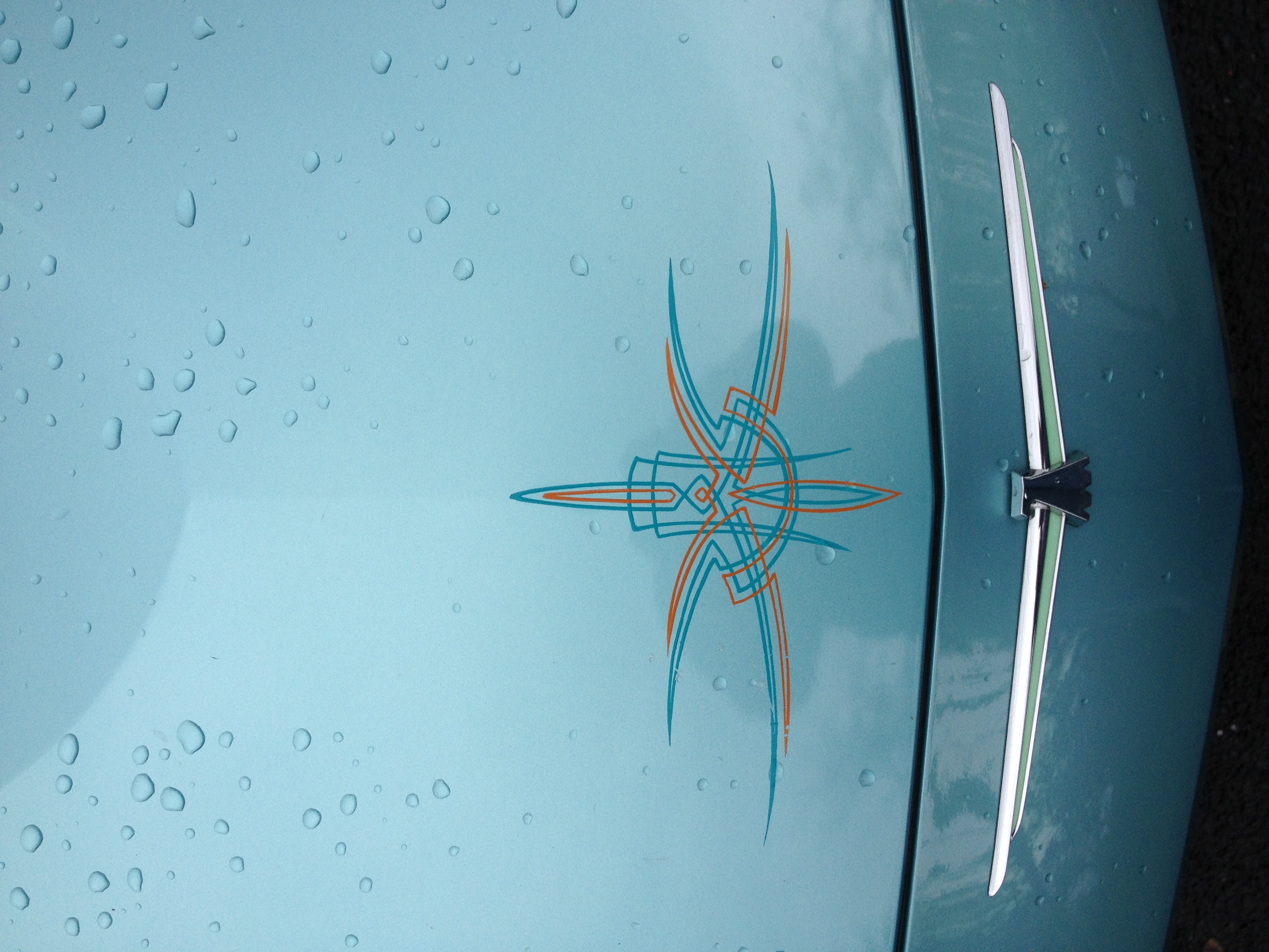 Teal and orange pinstripe star design on a car door panel