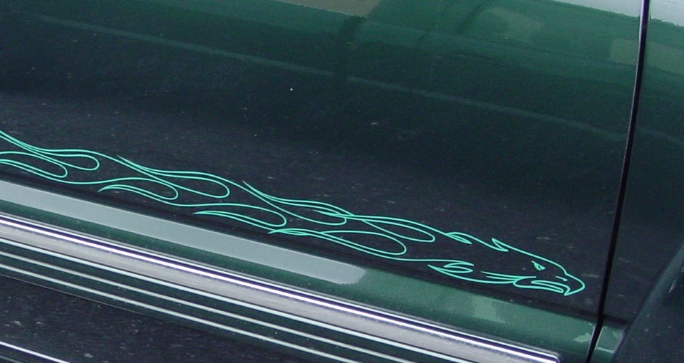 Close-up of hand-painted teal flame pinstriping on a car door