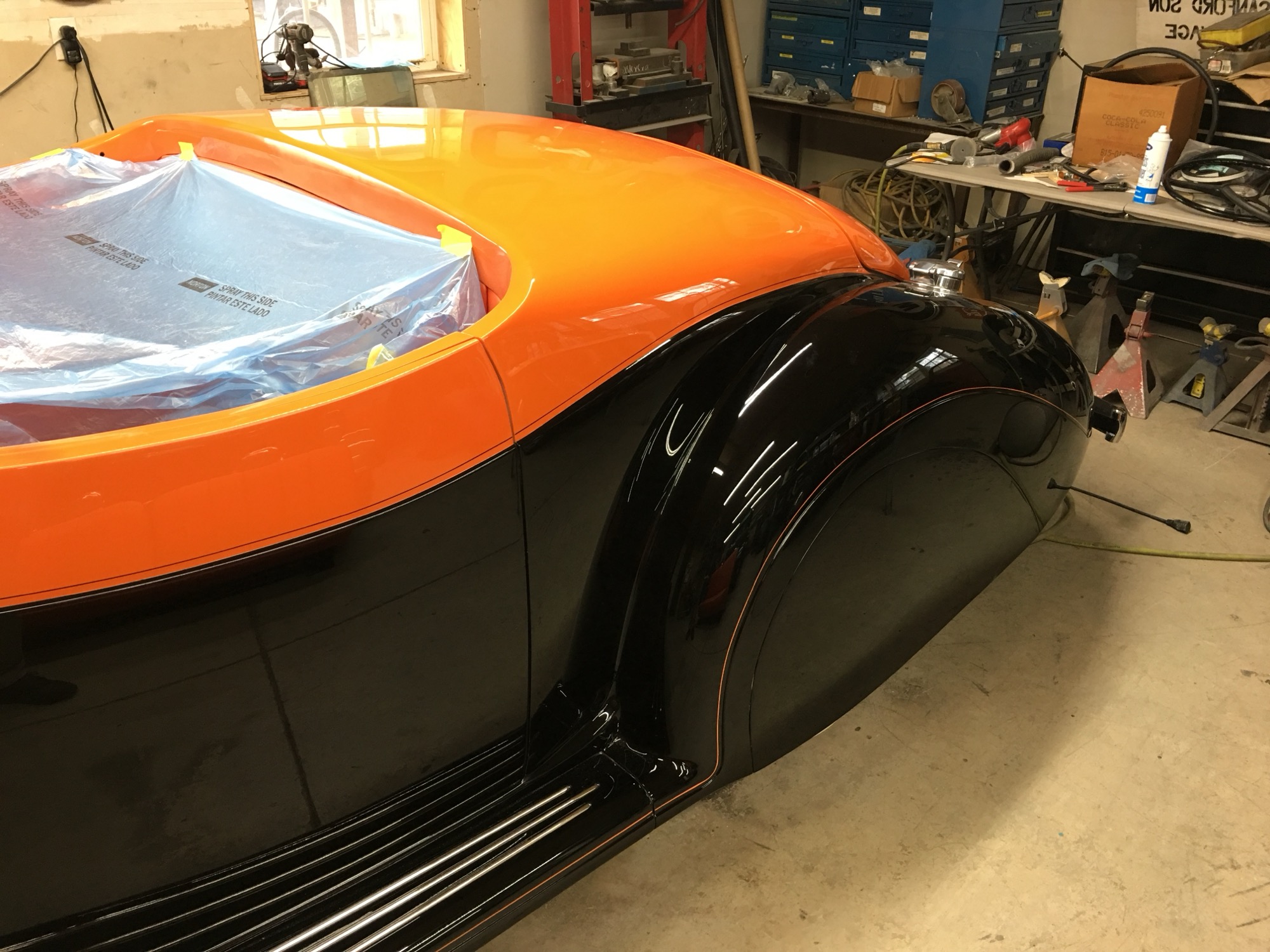 Close-up of the roadster's glossy black and orange paint along the fender and running board